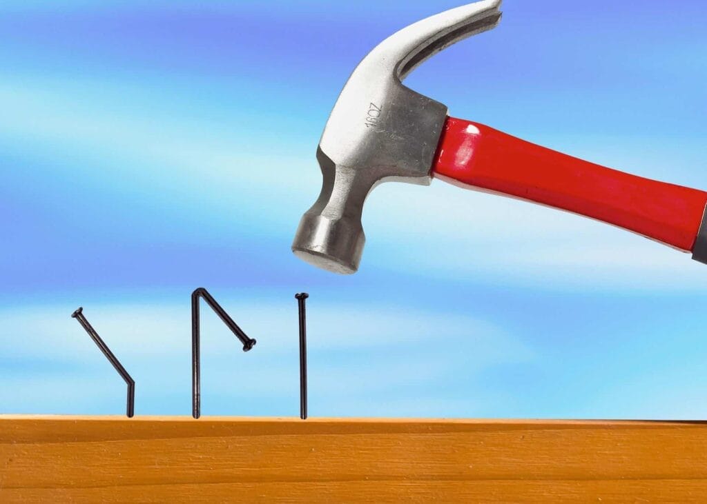 Hammer bending nails on wooden surface