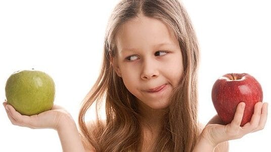 Child choosing between green and red apple.