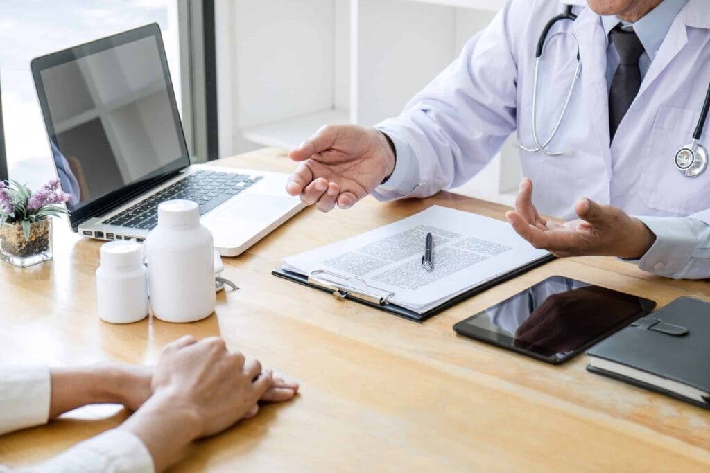 Doctor consulting patient with medical documents on desk.