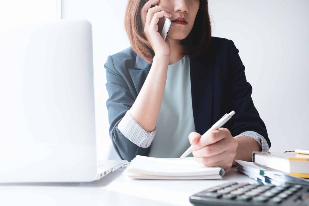 A woman is talking on the phone at her desk, although it is still in the preliminary stage.