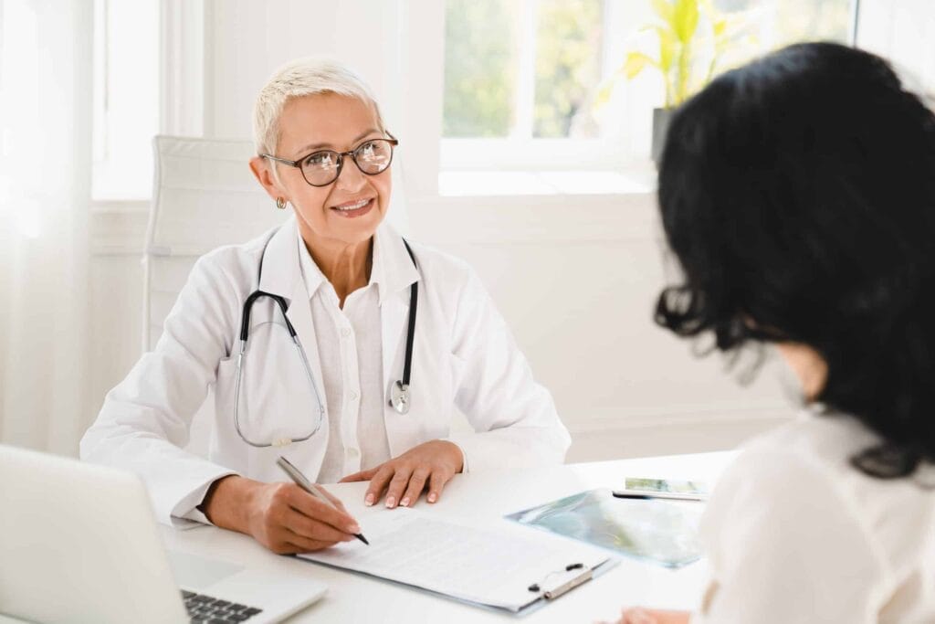 A doctor explaining the distinction between large group insurance and small group insurance to a patient at a desk.