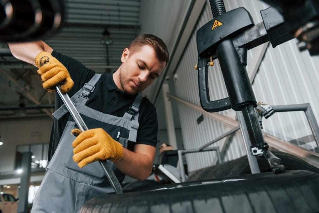 A mechanic complying with the PPACA mandates while working on a tire in a garage.
