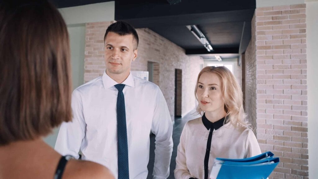 Two colleagues discussing employee benefits in a hallway.