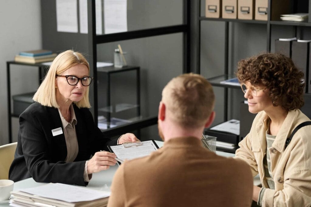 A group of insurance brokers sitting around a table in an office, discussing their clients' needs and services offered.