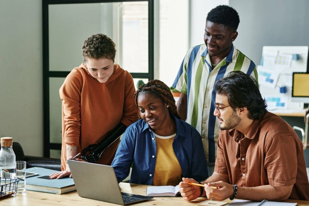 A group of people studying the laptop in an office.