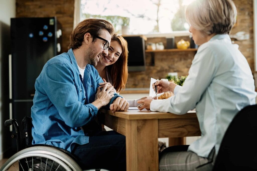 A woman and a man, both in wheelchairs, seated at a table pondering the importance of disability insurance.