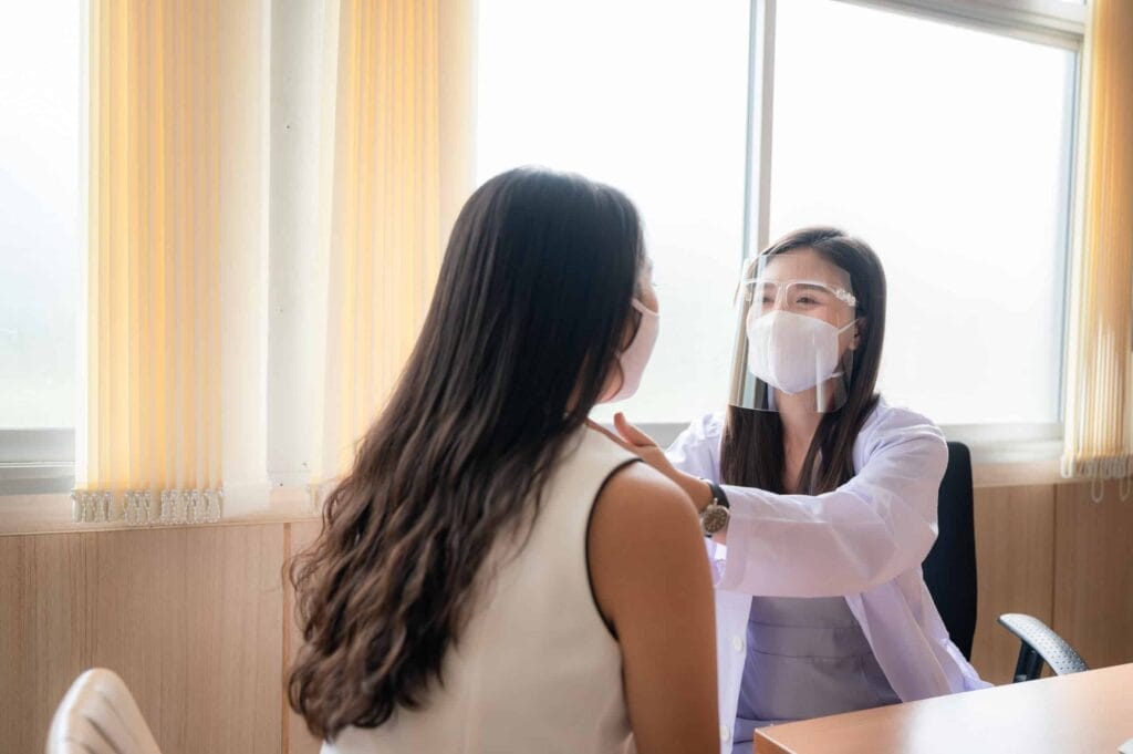 A masked woman undergoes a doctor's examination, considering the benefits of carving out her prescription.