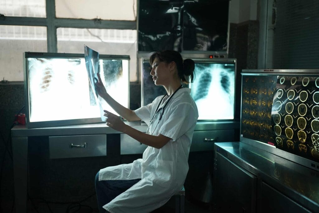 A woman in a lab analyzing x-rays to determine carriers' rates and benefits.