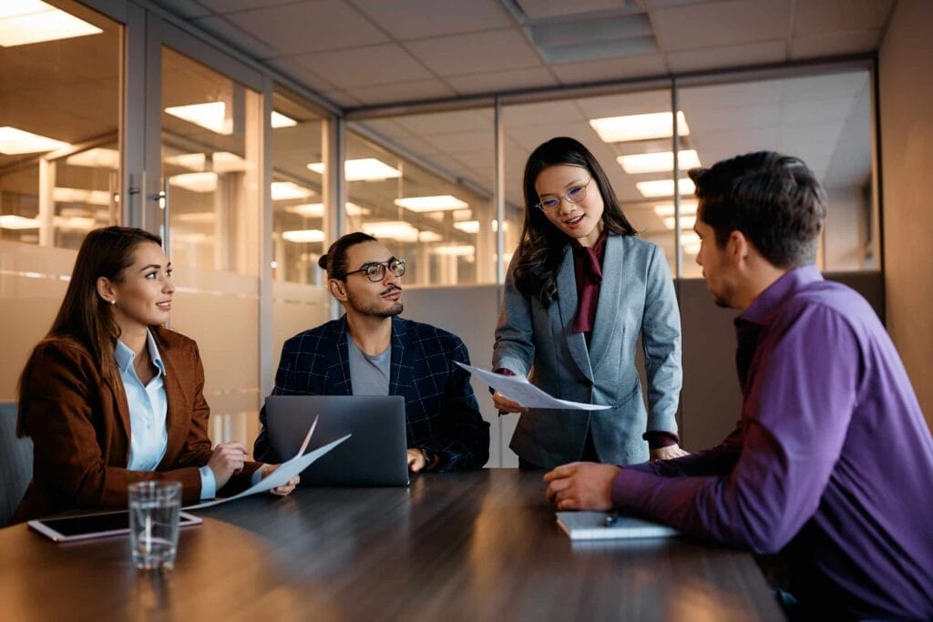 Inquisitive business people discussing PEOs and cost-effectiveness around a conference table.