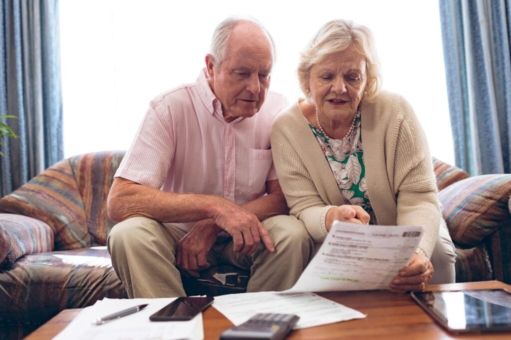 Older couple reviewing financial documents together on couch.