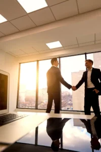 Two businessmen shaking hands in office meeting.